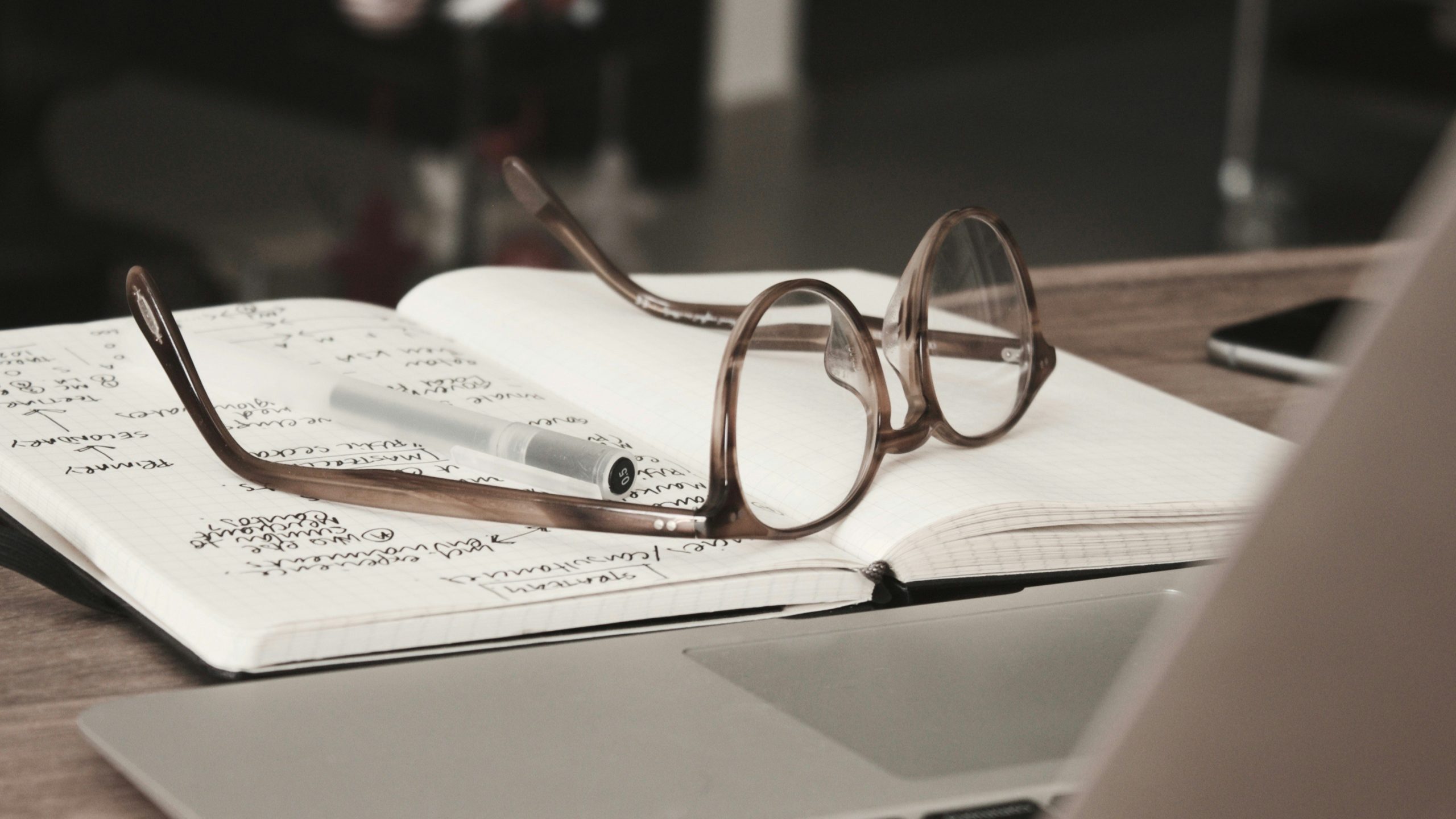 a pair of reading glasses laying on top of an open notebook