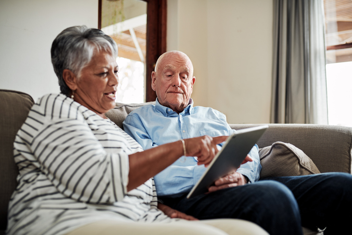 Two people sitting on a couch using an iPad